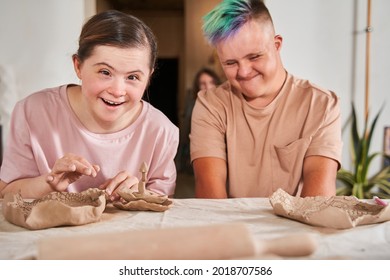 Boy with down syndrome smiling happily and looking at the dishes while making plates - Powered by Shutterstock