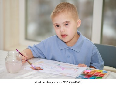 A boy with Down syndrome, trisomy 21, the child draws with watercolors.
