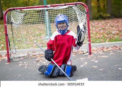 A boy dressed to be the goalie in a street hockey game
