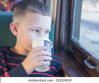 Boy Drinking Hot Chocolate While Looking Out The Window On The Polar Express Train Ride