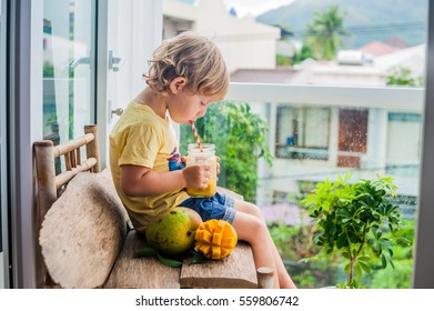 Boy Drinking Juicy Smoothie From Mango In Glass Mason Jar With Striped Red Straw On Old Wooden Background. Healthy Life Concept, Copy Space.