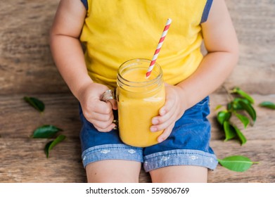 Boy Drinking Juicy Smoothie From Mango In Glass Mason Jar With Striped Red Straw On Old Wooden Background. Healthy Life Concept, Copy Space.