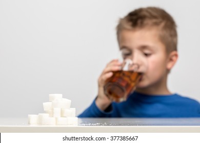 Boy Drinking Soft Drink / Soda, Next To It Is The Amount Of Sugar Used In It. Modern Day To Day Diet, Young People Drinking To Many Soft Drinks, Everyday Sugar Usage Among Children Concept Photo.