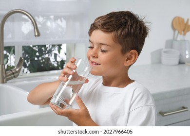 Boy Drinking Tap Water From Glass In Kitchen