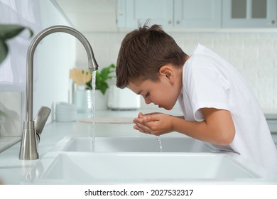 Boy Drinking Tap Water Over Sink In Kitchen