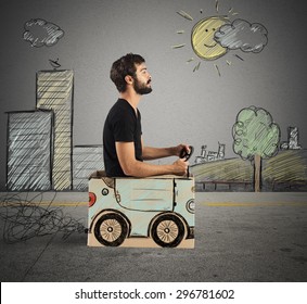 Boy Driving Cardboard Car In Drawing City