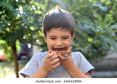 Boy Eating Bread With Jam Toast. Child Eats Sandwich With Jam For Breakfast