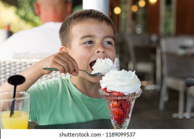 The Boy Is Eating Dessert. Strawberry With Cream