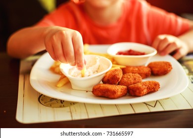 Boy Eating Fast Food In A Cafe. The Child Eating French Fries With Nuggets