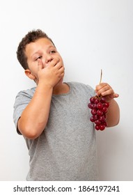 Boy Eating Grapes On A Light Background