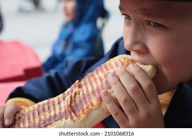 The Boy Is Eating A Grilled Sandwich.