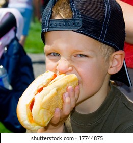 A boy eating a hot dog outdoors