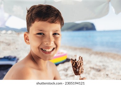 Boy eating an ice cream standing near seafront. Little boy on vacation treating himself to an ice cream. - Powered by Shutterstock