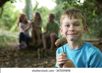 Boy Eating Sausage Around Camp With Friends