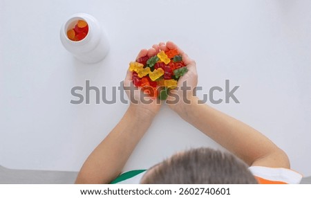 The boy eats jelly beans or takes vitamins.