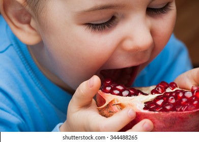 The boy eats a pomegranate - Shutterstock ID 344488265