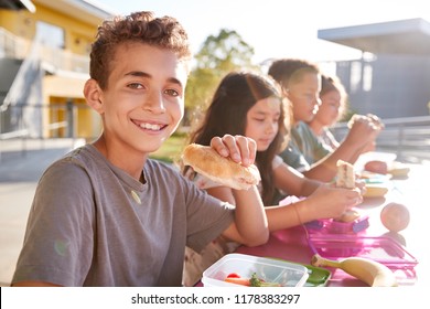 Boy At Elementary School Lunch Table Smiling To Camera