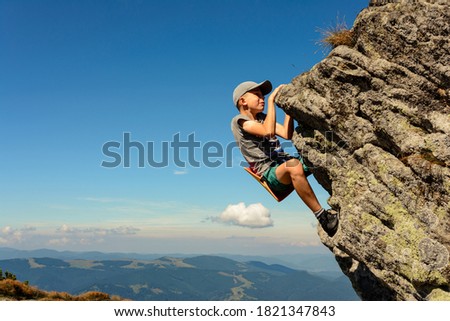 The boy is engaged in mountaineering, a child climbing a rocky mountain, a brave boy.