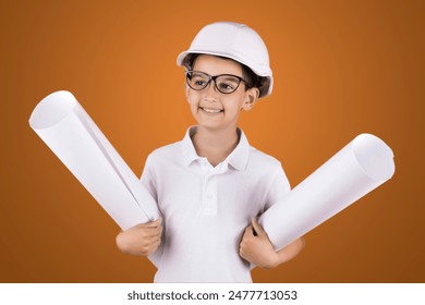 a boy engineer in a hard hat and glasses with blueprints on a blue background. studio photo.