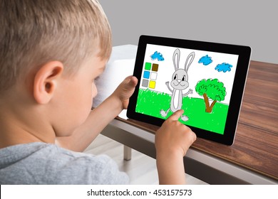 Boy Engrossed In Screen Of Digital Tablet While Playing Game