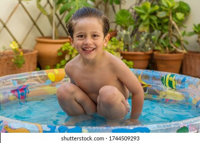 Boy Enjoying Summer In The Pool At Home. Boy Playing In The Kiddie Pool In The Backyard. Summer At Home Concept