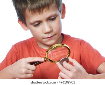 Boy Examines A Collector Silver Coin Through A Magnifying Glass