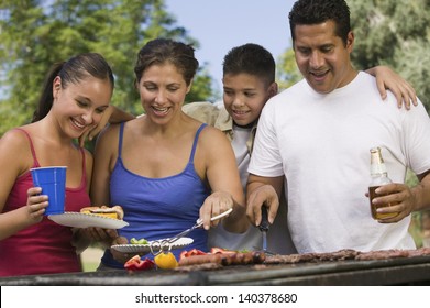 Boy with family gathered around the grill at picnic - Powered by Shutterstock