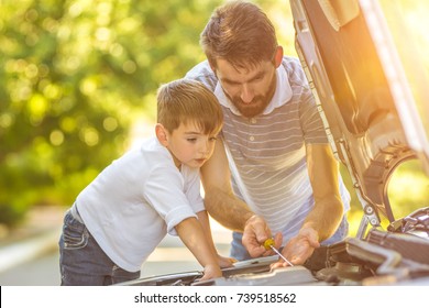 The boy and the father check the oil level in the car - Powered by Shutterstock