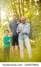 Boy, Father And Grandfather Holding Sticks In Forest