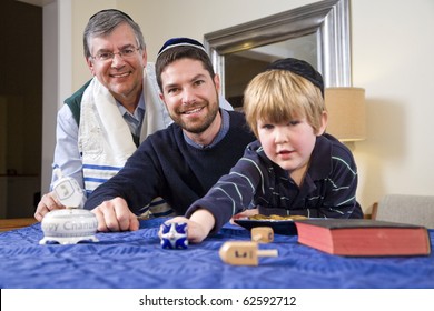 Boy with father and grandfather spinning dreidel, celebrating Hanukkah