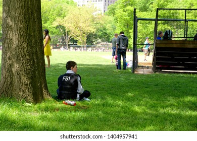 Boy In FBI Black Jacket Sitting Under The Shade Tree In Center Park New York, USA 18 May 2019