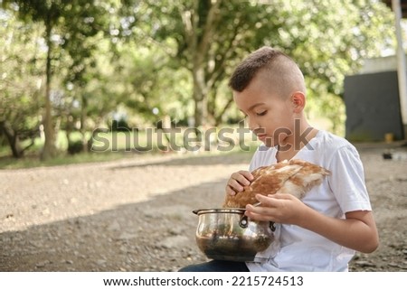 boy feeding a chicken in a pot in the field