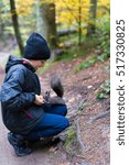 The boy feeds a squirrel with nutlets from a hand in the wood