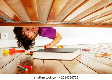 Junge findet Buch unter dem Bett, das sich nach unten lehnt und die Kamera ansieht