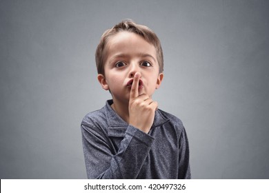 Boy with finger on lips making a silent gesture