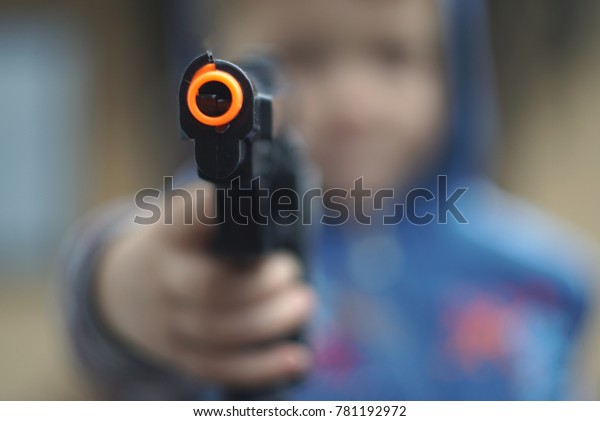 Boy fires with a toy gun pistol. focus on the gun\
                            \
