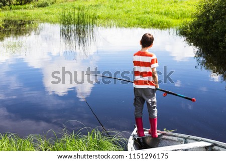 boy with the fishing rod standing on the boat. child fishing alone