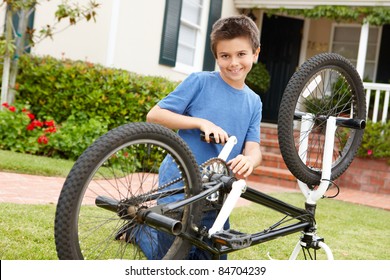 Boy Fixing Bike In Garden