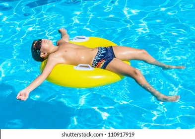 Boy Floating On An Inflatable Circle In The Pool. A Child In The Pool