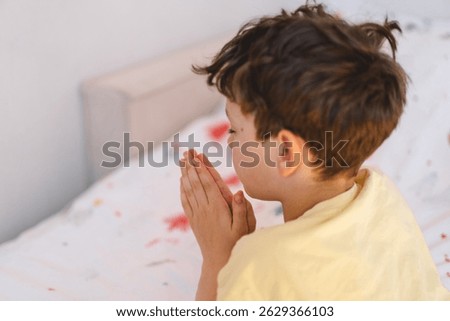 A boy with folded hands in front of him, he is praying or meditating. Concept of Christianity, religion and faith.
