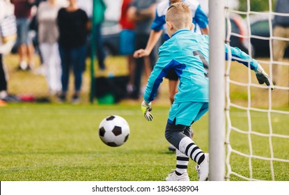 Boy Football Goalie In Action. Young Soccer Goalkeeper Running Towards Soccer Ball. Child Goalie Soccer Save On School Tournament