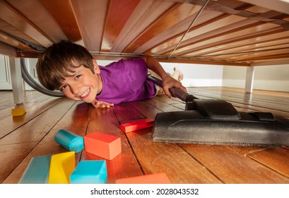 Boy gets under bed vacuum clean floor in his room with a lot of color blocks