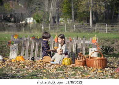 Boy, girl and a baby in the autumn park playing with pumpkin - Shutterstock ID 517893622