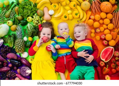 Boy, girl and baby with variety of fruit and vegetable. Colorful rainbow of raw fruits and vegetables. Child eating healthy snack. Vegetarian nutrition for kids. Vitamins for children. View from above