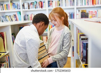 Boy And Girl Carry Books Together In The School's Library
