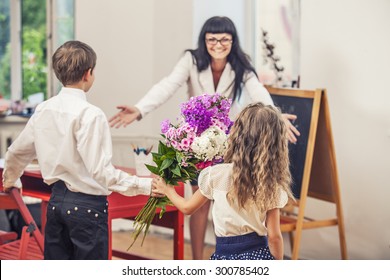 Boy And Girl Children Give Flowers As A School Teacher In Teacher's Day