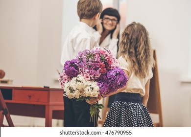 Boy And Girl Children Give Flowers As A School Teacher In Teacher's Day