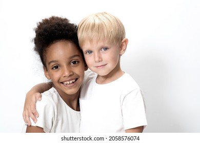 Boy and  girl, of different ages children hugging on a white studio background. Happy kids, friendship, friends, adoption, different skin color, cool team concept. 
