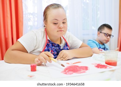 Boy and girl with Down syndrome draw at a table on a white background. High quality photo