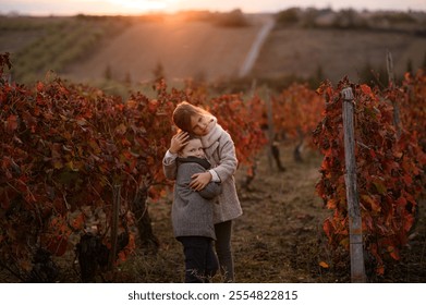 A boy and a girl embrace in a red vineyard during autumn, surrounded by the vibrant colors of fall. The warm hues of the foliage create a cozy, intimate atmosphere as they share a tender
 - Powered by Shutterstock